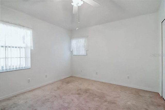 carpeted spare room with baseboards and ceiling fan