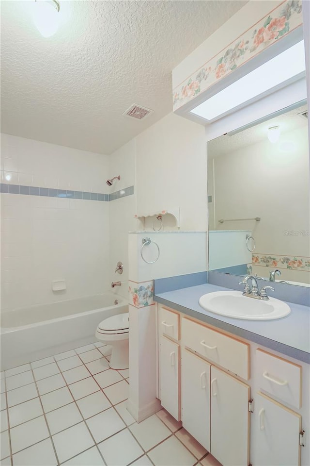 full bathroom featuring tiled shower / bath, vanity, a textured ceiling, toilet, and tile patterned floors