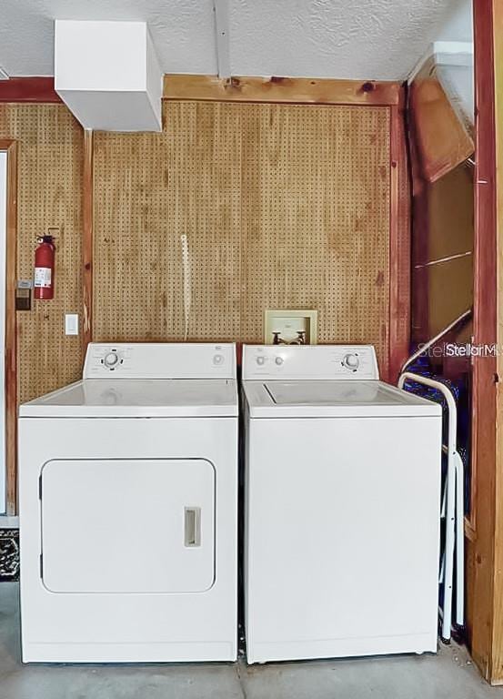 washroom featuring wallpapered walls, laundry area, separate washer and dryer, and a textured ceiling