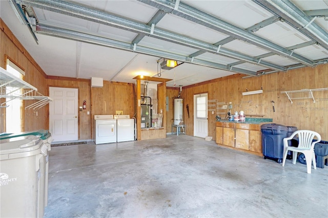 garage featuring a garage door opener, water heater, a workshop area, wooden walls, and separate washer and dryer