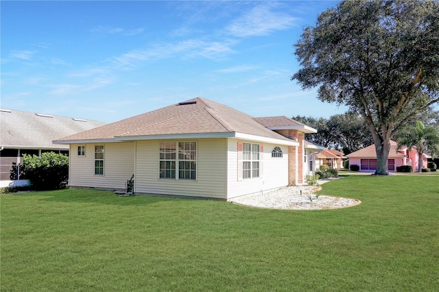 back of property featuring a yard and a shingled roof