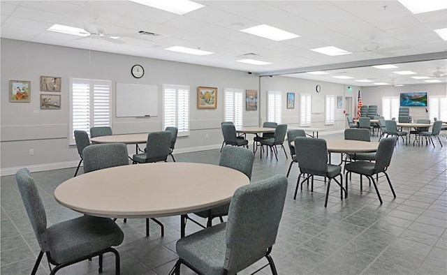 tiled dining area with visible vents, a paneled ceiling, baseboards, and ceiling fan