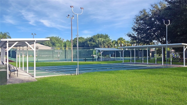 view of property's community featuring a lawn, shuffleboard, and fence