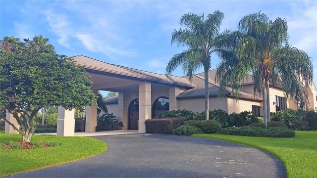 exterior space featuring aphalt driveway, a front lawn, and stucco siding