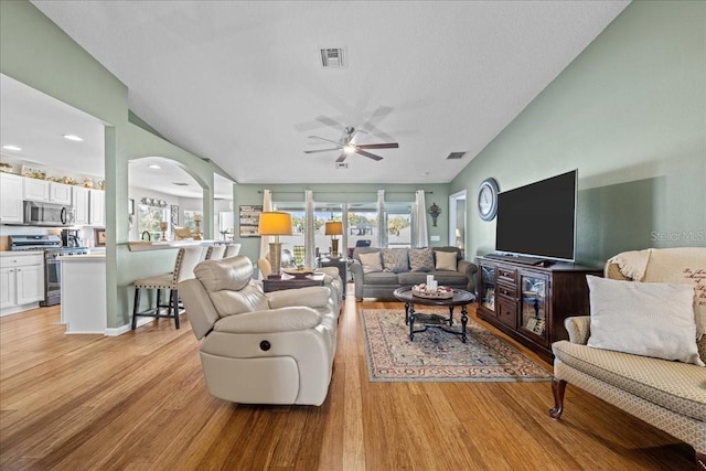 living room featuring ceiling fan, vaulted ceiling, and light hardwood / wood-style floors