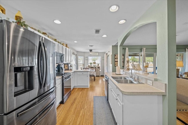 kitchen featuring plenty of natural light, stainless steel appliances, white cabinetry, and sink