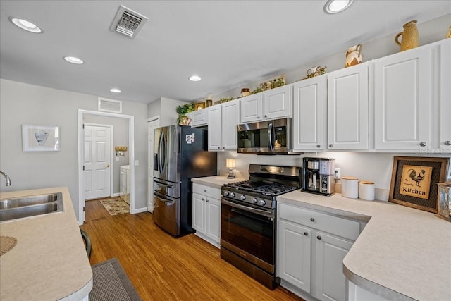 kitchen with light hardwood / wood-style flooring, appliances with stainless steel finishes, white cabinetry, and sink