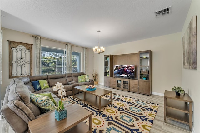 living room featuring light hardwood / wood-style floors, a chandelier, and a textured ceiling