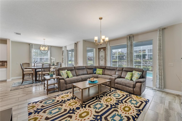 living room with a textured ceiling, a notable chandelier, and light hardwood / wood-style floors