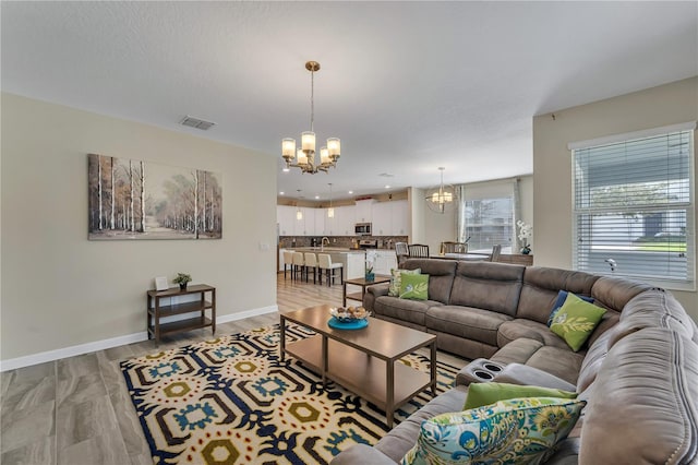 living room with light wood-type flooring, sink, a chandelier, and a textured ceiling