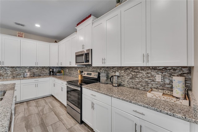 kitchen with light stone counters, stainless steel appliances, white cabinets, and decorative backsplash