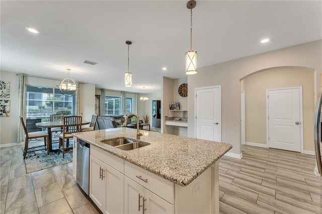 kitchen featuring white cabinets, dishwasher, light stone counters, sink, and a kitchen island with sink