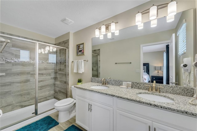 bathroom with vanity, toilet, a shower with shower door, and a textured ceiling