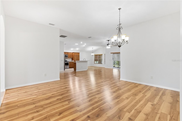 unfurnished living room with ceiling fan with notable chandelier and light hardwood / wood-style floors