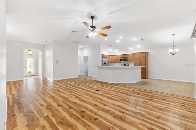 unfurnished living room featuring light hardwood / wood-style flooring and ceiling fan with notable chandelier