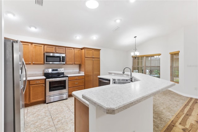 kitchen featuring light wood-type flooring, decorative light fixtures, stainless steel appliances, lofted ceiling, and an island with sink