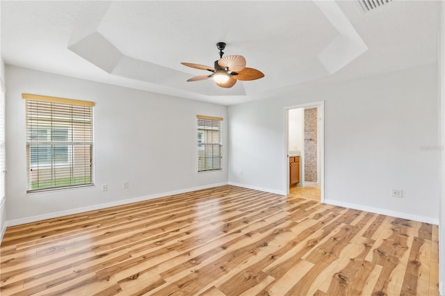 unfurnished room featuring a tray ceiling, ceiling fan, and light hardwood / wood-style floors