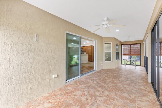 unfurnished sunroom featuring ceiling fan