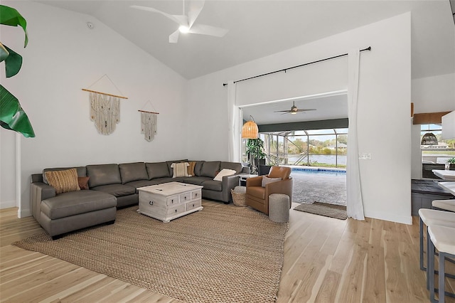 living room with ceiling fan, light wood-type flooring, and lofted ceiling