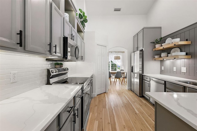 kitchen with appliances with stainless steel finishes, gray cabinetry, and light stone countertops