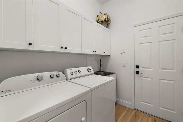 clothes washing area with cabinets, separate washer and dryer, sink, and light hardwood / wood-style flooring