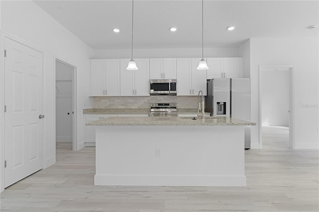 kitchen with white cabinets, appliances with stainless steel finishes, and a center island with sink