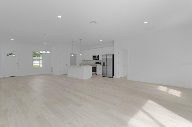 unfurnished living room featuring a notable chandelier, sink, and light hardwood / wood-style floors