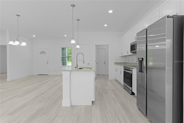 kitchen featuring decorative light fixtures, stainless steel appliances, sink, light stone countertops, and light hardwood / wood-style floors