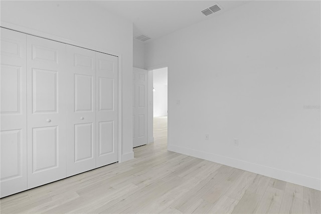 unfurnished bedroom with a closet and light wood-type flooring