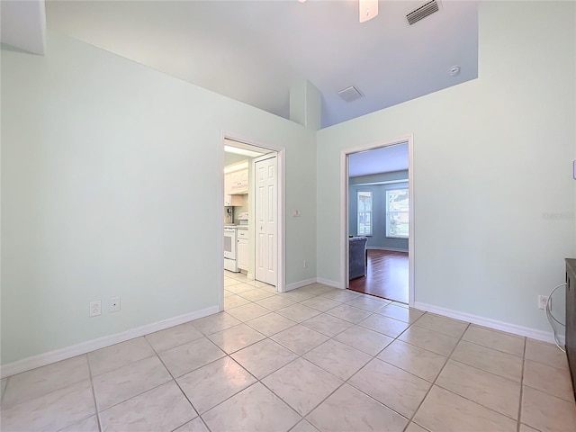 tiled spare room featuring vaulted ceiling