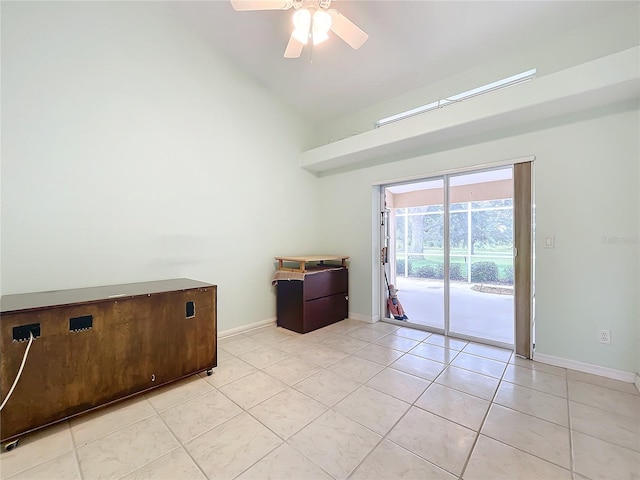 empty room with ceiling fan, light tile patterned floors, and vaulted ceiling