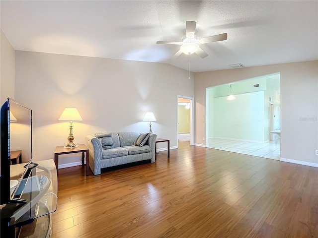 living room featuring lofted ceiling, wood-type flooring, ceiling fan, and a textured ceiling