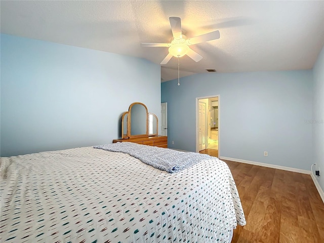 bedroom with a textured ceiling, ensuite bath, ceiling fan, lofted ceiling, and hardwood / wood-style flooring