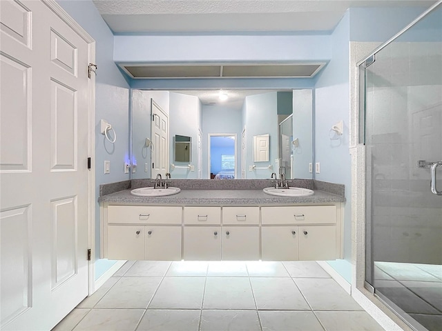 bathroom with a shower with door, vanity, and tile patterned floors