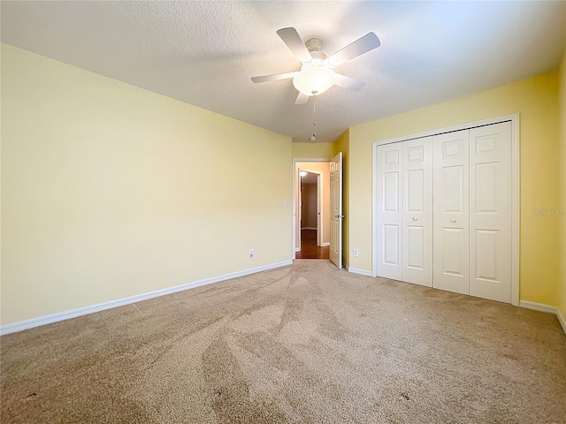 unfurnished bedroom with a textured ceiling, light colored carpet, ceiling fan, and a closet