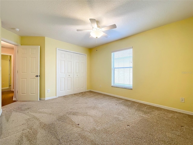 unfurnished bedroom featuring light carpet, a textured ceiling, ceiling fan, and a closet