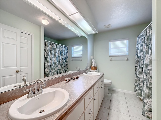 bathroom featuring plenty of natural light, vanity, toilet, and tile patterned floors