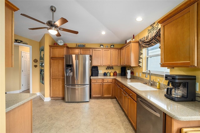 kitchen featuring vaulted ceiling, light stone countertops, stainless steel appliances, ceiling fan, and sink