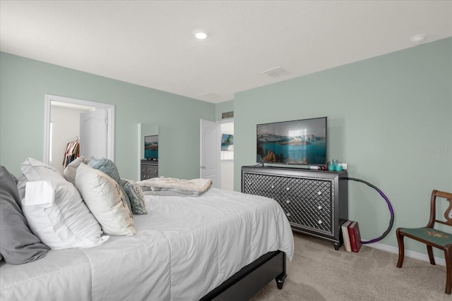 bedroom with a closet, a spacious closet, and light carpet