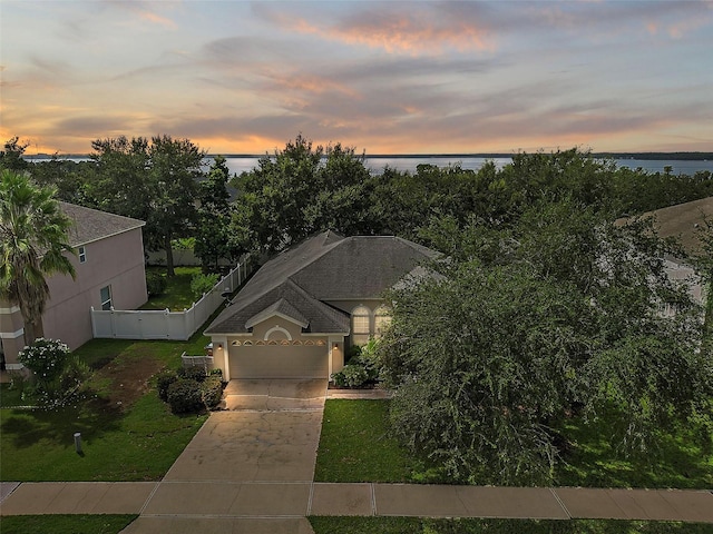 view of front of house featuring a lawn, a garage, and a water view