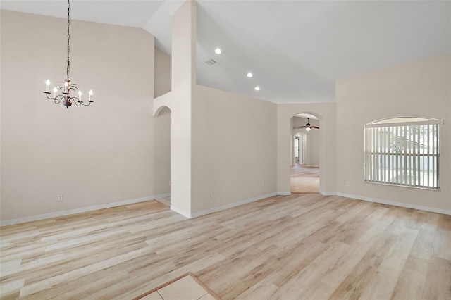 unfurnished living room with ceiling fan with notable chandelier, high vaulted ceiling, and light hardwood / wood-style floors