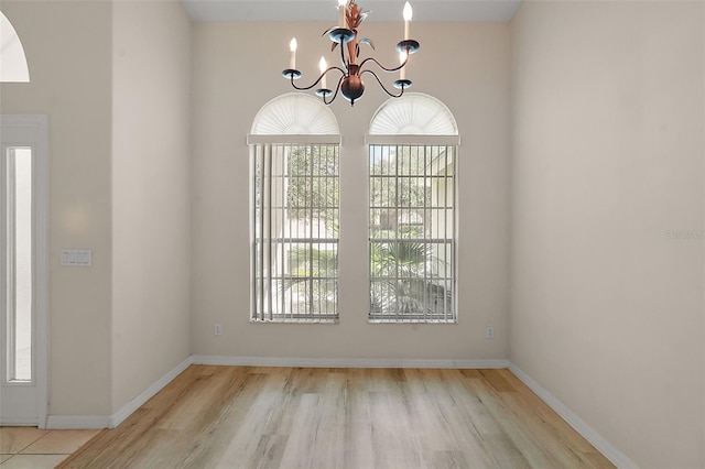 unfurnished dining area featuring a chandelier and light hardwood / wood-style flooring