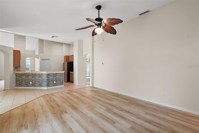 unfurnished living room featuring lofted ceiling, light hardwood / wood-style flooring, and ceiling fan