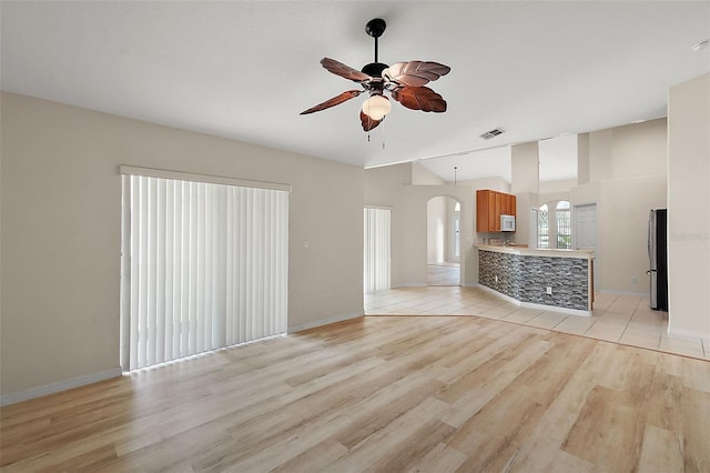 unfurnished living room featuring light wood-type flooring, lofted ceiling, and ceiling fan