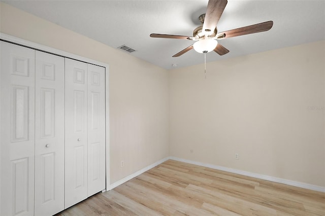 unfurnished bedroom featuring light wood-type flooring, ceiling fan, and a closet