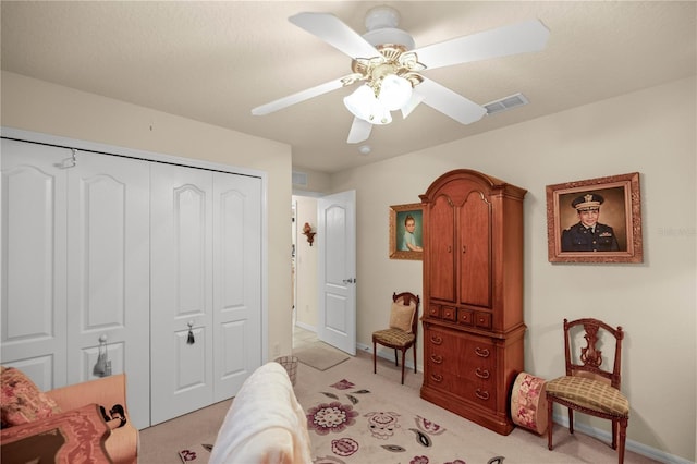 bedroom featuring a textured ceiling, light colored carpet, ceiling fan, and a closet