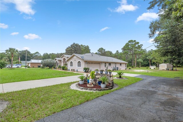 ranch-style home featuring a garage, a front lawn, and a storage unit