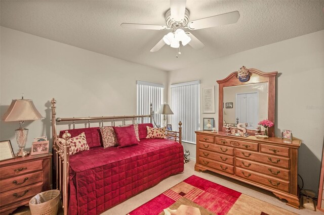 carpeted bedroom featuring a textured ceiling and ceiling fan