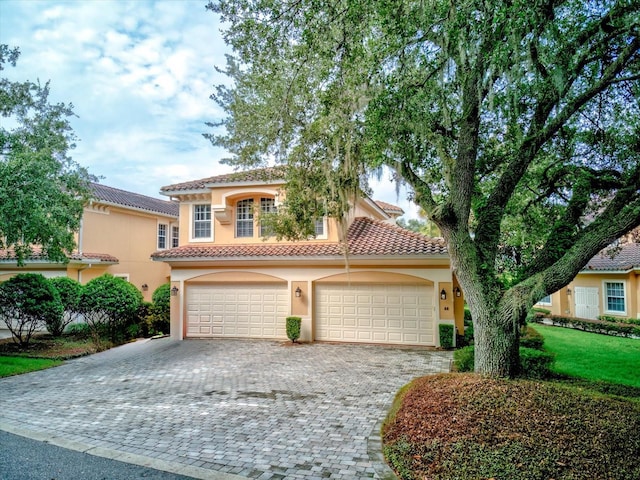 mediterranean / spanish home featuring a garage and a front lawn