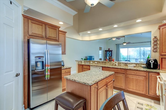 kitchen with light tile patterned floors, white appliances, ceiling fan, kitchen peninsula, and a kitchen breakfast bar